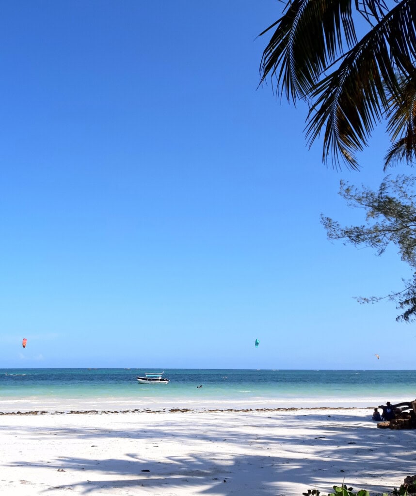 Ein weißer Sandstrand mit palmenschatten in Diani.