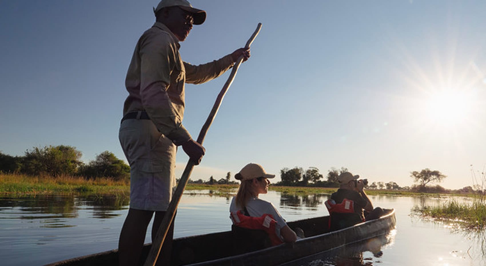 Gäste in einem Einbaumkanu in Botswana.
