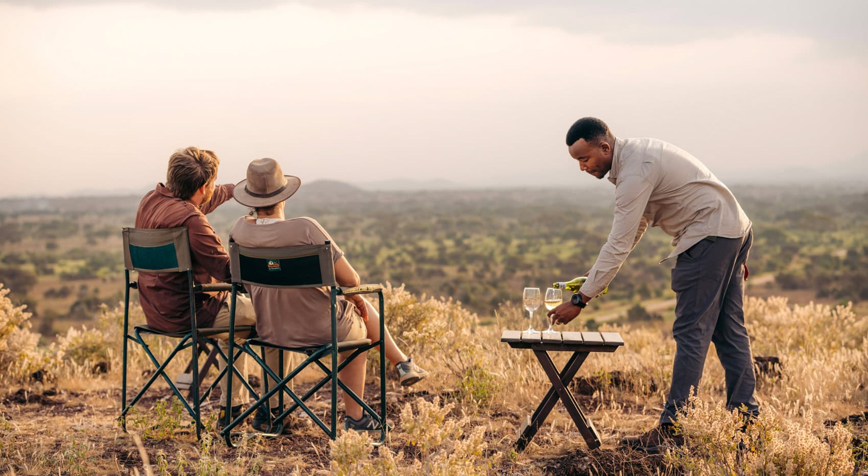 Ein Pärchen beim Sundowner mit Kellner und Wein in Tansania. Ein Pärchen beim Sundowner mit Kellner und Wein in Tansania.