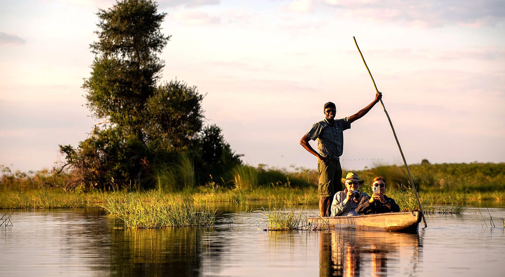 Gäste mit ihrem Guide im Okavango Delta in einem Einbaum Kanu. Gäste mit ihrem Guide im Okavango Delta in einem Einbaum Kanu.