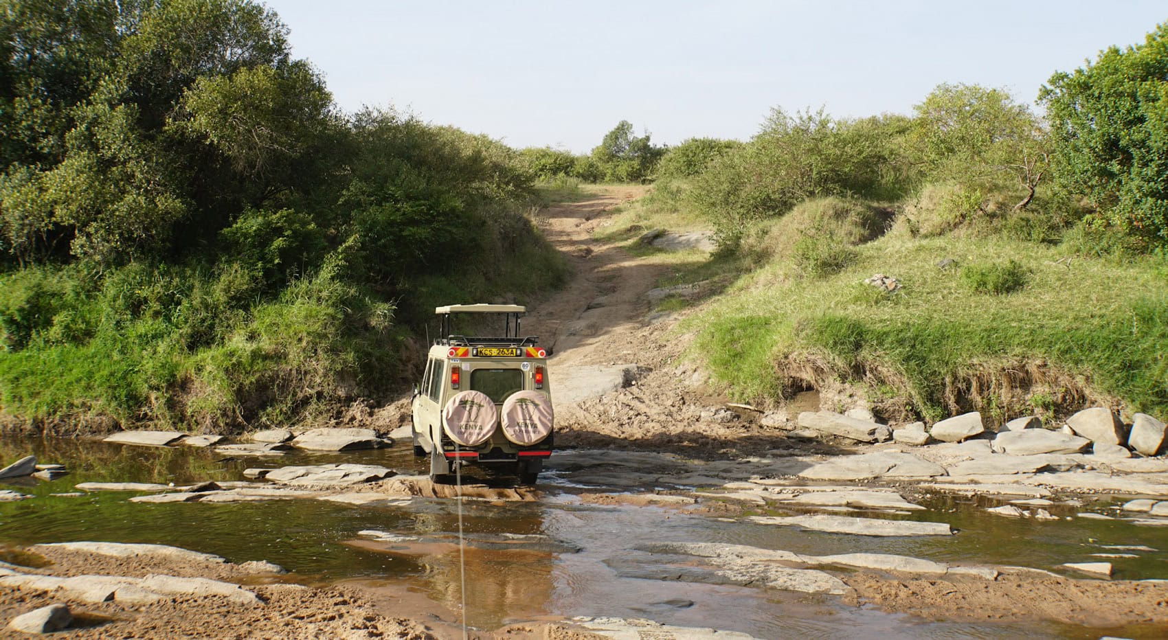 Ein Safari Fahrzeug durchquert einen Fluss in der Masai Mara in Kenia. Ein Safari Fahrzeug durchquert einen Fluss in der Masai Mara in Kenia.