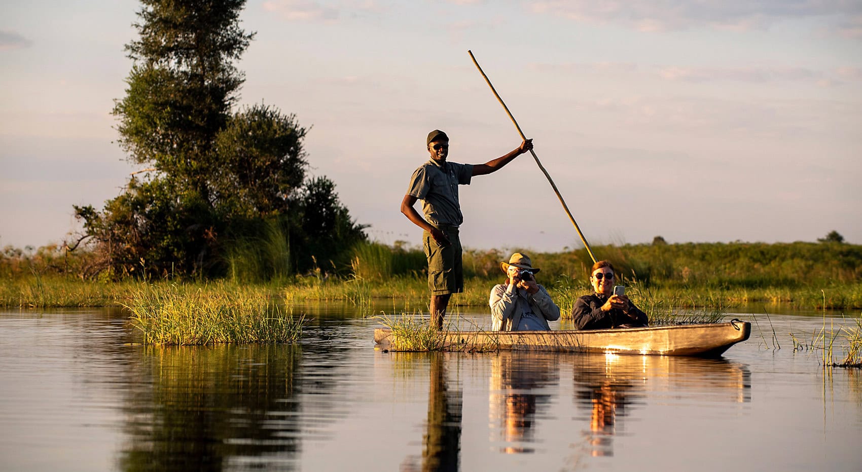Ein Guide mit seinen Gästen in einem Mokoro im Okavango Delta. Ein Guide mit seinen Gästen in einem Mokoro im Okavango Delta.